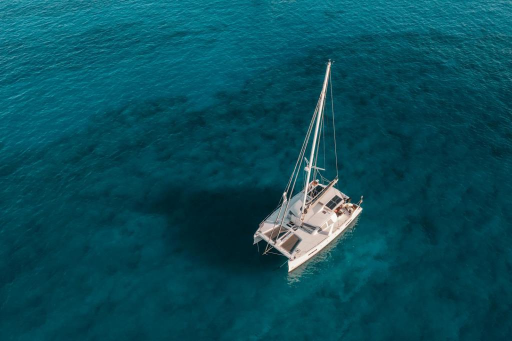 A serene aerial shot of a catamaran sailing on crystal blue waters, perfect for travel and marine themes.