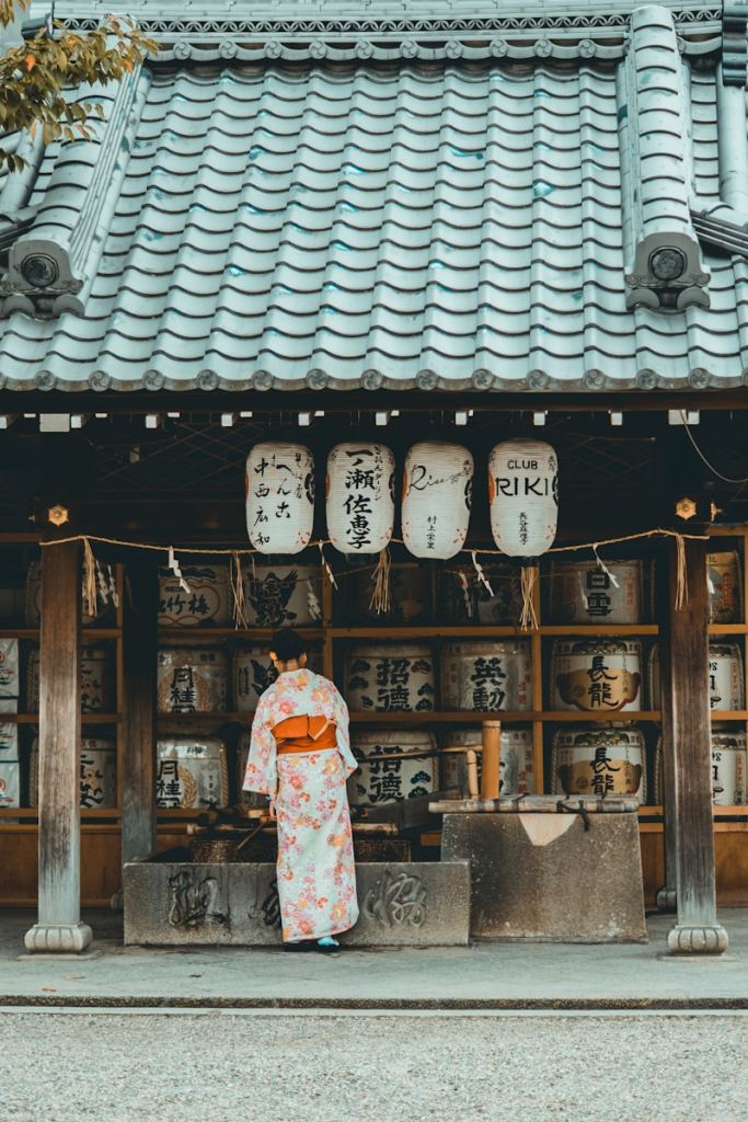woman wearing orange and white kimono dress standing near the house